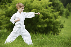 One little boy in white kimono during training karate kata exercises in summer outdoors